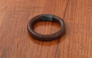 Macro del cinturino in pelle intrecciata marrone scuro con trama dettagliata su legno
