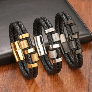 Three men's braided leather bracelets with gold, silver and black metal clasps on wood