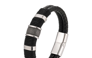 Dettaglio di un bracciale in pelle nera intrecciata con anelli metallici e chiusura magnetica