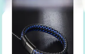 Macro detail of braided black leather bracelet with blue stitching and metal magnetic clasp