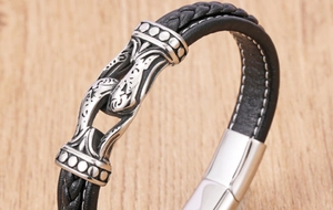 Macro shot of black braided leather men's bracelet with silver tribal pattern engraving