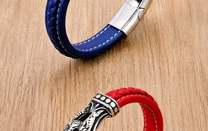 Detail of woven leather bracelets in navy blue and red with metal clasps on wood