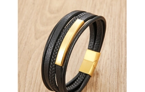 Detail of multi-layer black leather bracelet with a polished gold metal plate and magnetic clasp