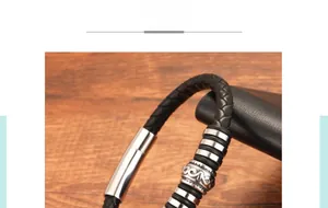 Macro shot of black braided leather bracelet with engraved silver metal beads and clasp