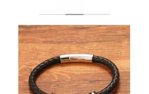 Close-up of black braided leather bracelet with polished silver metal buckle on wood