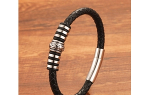 Detailed macro view of woven black leather bracelet with silver totem beads and magnetic clasp
