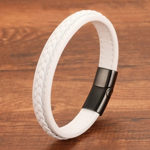 Detail of white braided leather bracelet with black magnetic clasp on wood background