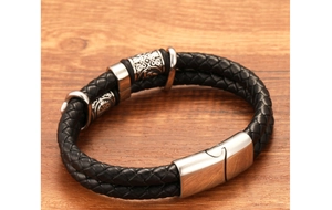 Close-up of black braided leather men's bracelet with silver magnetic clasp on wood