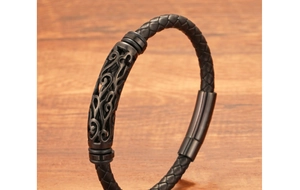 Dettaglio del bracciale da uomo in pelle nera intrecciata con tubo in metallo inciso