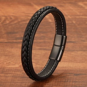 Detail of black braided leather bracelet with white stitching and magnetic metal buckle