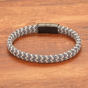 Détail d'un bracelet en cuir tressé fait main avec motif gris blanc et fermoir magnétique noir