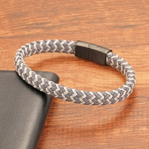 Détail d'un bracelet en cuir tressé avec fermoir magnétique noir mat sur surface boisée
