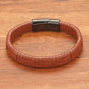 Detail of brown braided leather bracelet with black magnetic clasp on wood background