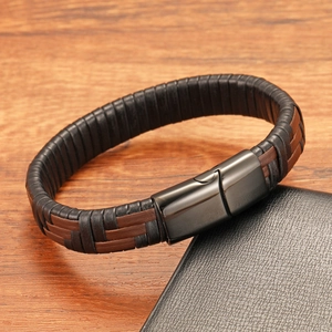 Close-up of braided leather bracelet with gunmetal magnetic clasp on a wooden surface