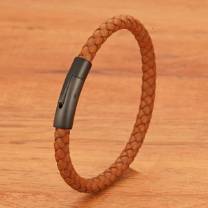Bruine gevlochten leren armband met zwarte matte metalen sluiting op houten basis