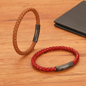 Detail van gevlochten leren armbanden in bruin en rood met matzwarte metalen sluiting