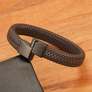 Close-up of brown braided leather bracelet with matte black industrial metal buckle detail