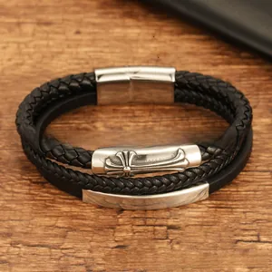 Macro detail of men's layered black leather bracelet with cross pattern metal clasp