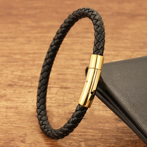 Close-up of black braided leather bracelet with a polished gold cylindrical clasp