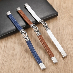 Detail van gevlochten leren armbanden in blauw, bruin en wit met metalen knoopaccenten
