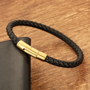 Detail shot of men's braided black leather bracelet with a polished gold stainless steel clasp
