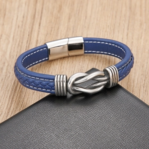 Detail van blauw gevlochten leren armband met zilveren knoop-element en magnetische sluiting