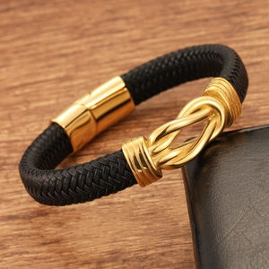 Men's black braided leather bracelet with gold infinity knot on rustic wood background