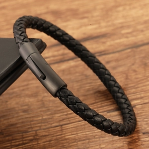 Braided black leather bracelet for men with a matte black metal clasp on wood