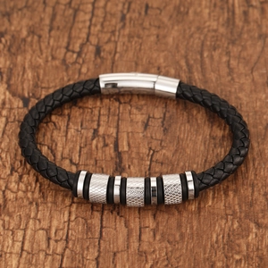 Close-up of black braided leather bracelet with stainless steel beads on wood