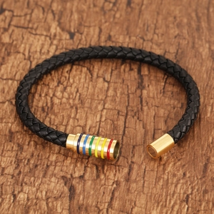 Braided black leather bracelet with a gold rainbow magnetic clasp on dark wood surface