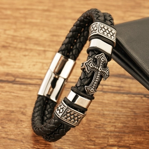 Men's double-row braided leather bracelet with engraved cross charm on wooden background