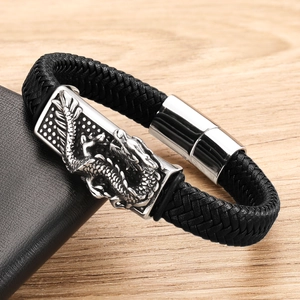 Close-up of black braided leather bracelet featuring a silver dragon relief buckle