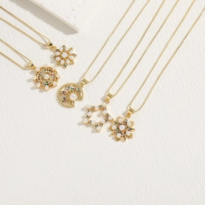 Close-up of five gold necklaces with star, moon, and pearl charms on textured background