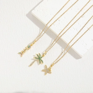 Macro shot of 14K gold plated necklaces with zircon fishbone, palm tree and starfish charms