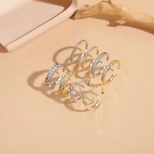 Collection de bagues géométriques en zircon doré et argenté sur fond beige chaleureux