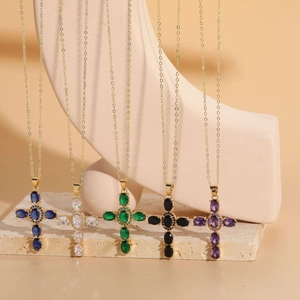 Detalle de cinco colgantes de cruz bañados en oro de 14K con piedras de circonita de colores