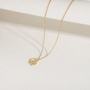 Macro shot of 14K gold unicorn pendant necklace with pavé zircon on white stone stand