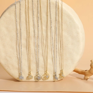 Macro shot of 14K gold plated necklaces featuring unicorn and leaf charms with zircon