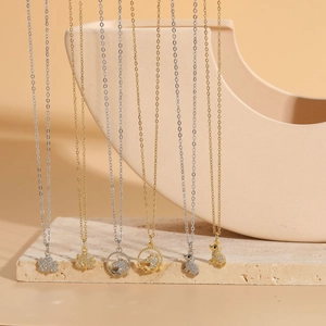 Macro shot of 14K gold-plated animal pendants with cubic zirconia on stone tiles