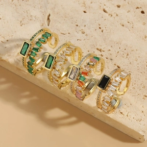 Bagues plaquées or 14K avec zircons carrés colorés disposées sur un support en pierre