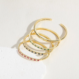 Detailed view of four gold-plated bangles with pink, blue, and green zircon gemstones