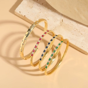 Detail of four-piece gold bracelet set featuring zircon stars and colorful gemstones