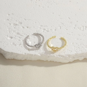Anillos abiertos de corazón con piedras de circón en acabados oro y plata sobre piedra