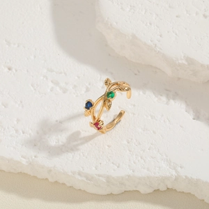 Detailed close-up of vine leaf ring with red, blue, and green zircon stones on stone background