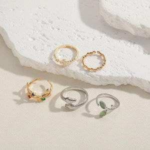 Five-piece ring set with cat-eye stones and snake designs on elegant mineral background