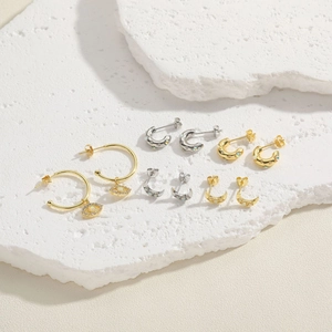 Golden and silver moon opal evil eye earring set displayed on a white textured stone background