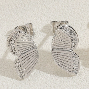 Detailed macro view of silver butterfly wing earrings with fine radial textures and beads