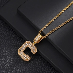 Close-up of golden letter C pendant necklace with sparkling zircons on a black base