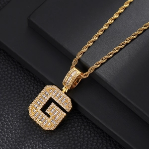 Macro detail of gold letter G pendant necklace with cubic zirconia on black leather
