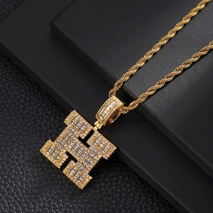 Macro view of gold plated necklace featuring a large iced out H letter pendant with zircons